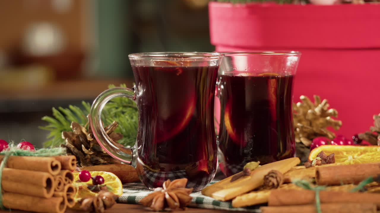 Hände stellen heißen Glühwein auf einen festlichen Weihnachtstisch
