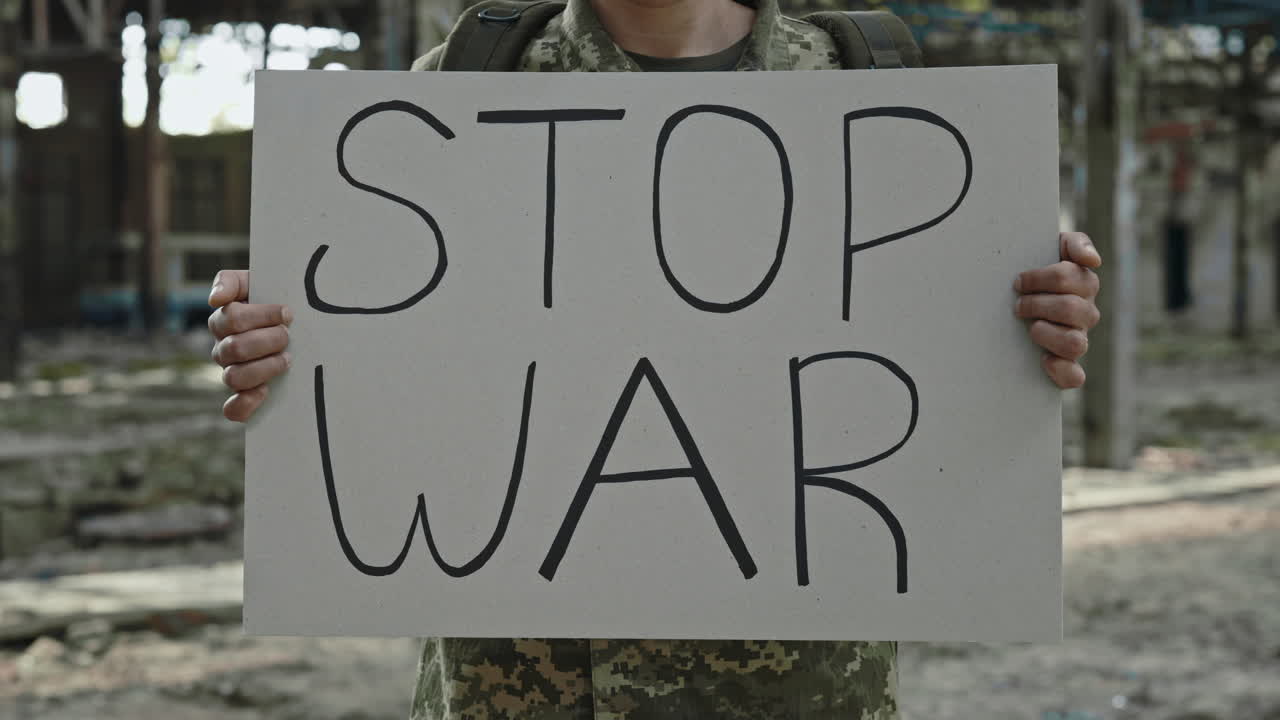 Soldier Holding Anti-War Sign in War Zone