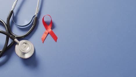 Video-of-stethoscope-and-red-blood-cancer-ribbon-on-blue-background