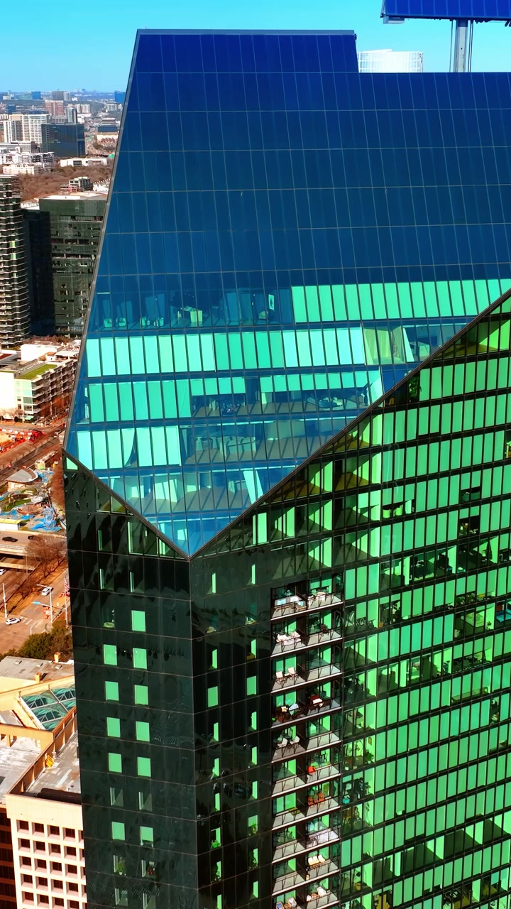 Scendendo lungo la facciata di un moderno grattacielo che riflette la luce del sole. Vista panoramica di Dallas, Texas, USA dall'alto. Video verticale.