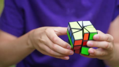 boy in blue t-shirt holding rubik's cube. teenage boy playing with square colorful toy. rubik's cube in new form in child's hands. close-up.
