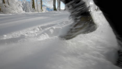 legs running in deep fresh snow in winter through the forest in slow motion with a lot of snow particles flying in the air