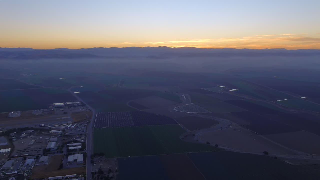 vista aérea de los campos que rodean la pequeña ciudad con el sol saliendo por encima de las montañas