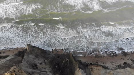 Aerial-view-of-the-steep-slopes-and-waves-at-Rubjerg-Knude-by-the-North-Sea,-Denmark