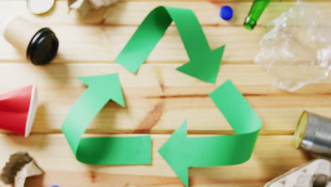 cierre de la basura y el símbolo de reciclaje de flechas de papel verde sobre fondo de madera