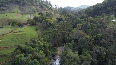 Drone-camera-movement-downwards-revealing-a-beautiful-waterfall-in-the-middle-of-the-forest