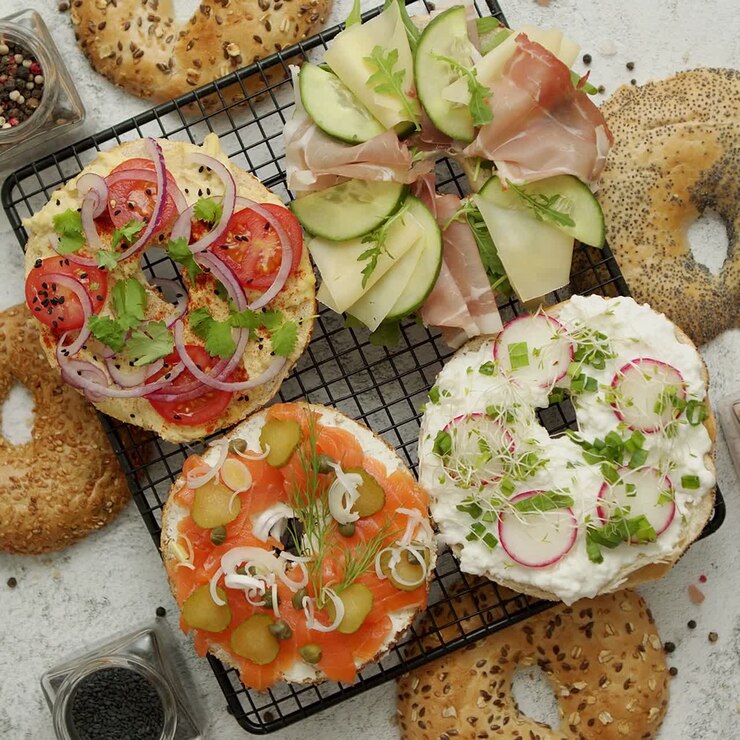 Deliziosi bagel farciti con formaggio cremoso, prosciutto, hummus, salmone e verdure