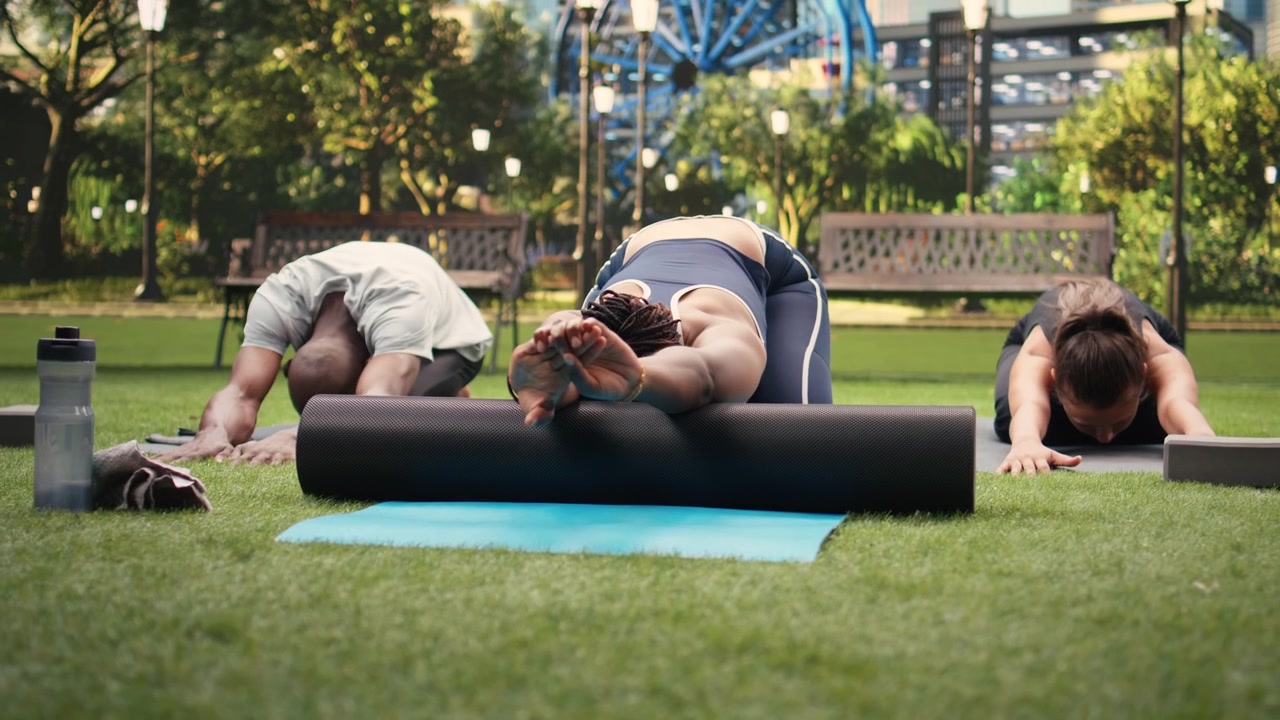 Participants sitting in child pose on foam roller on yoga mat