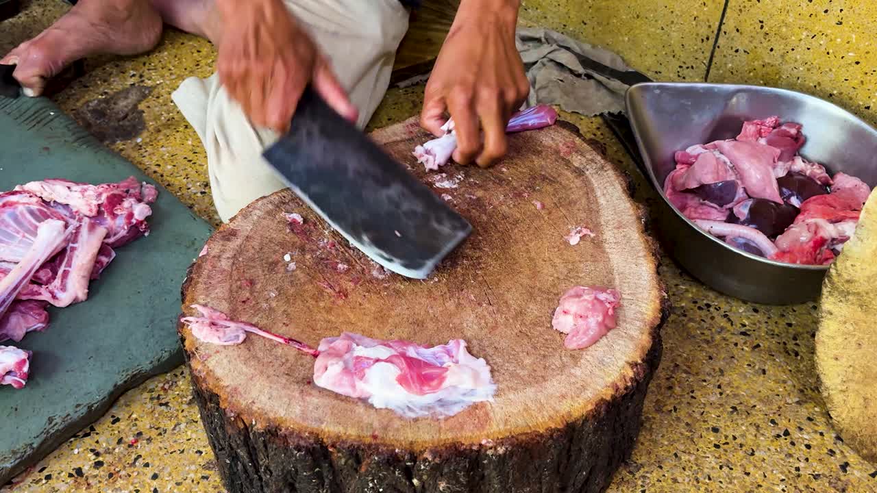 Närbild av en slaktare som skär kött med traditionella verktyg på träbänkar.