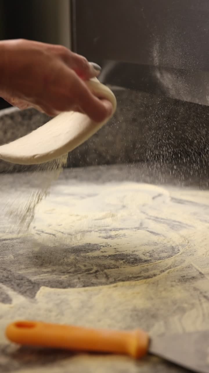 Mani che lanciano l'impasto della pizza con farina sul bancone
