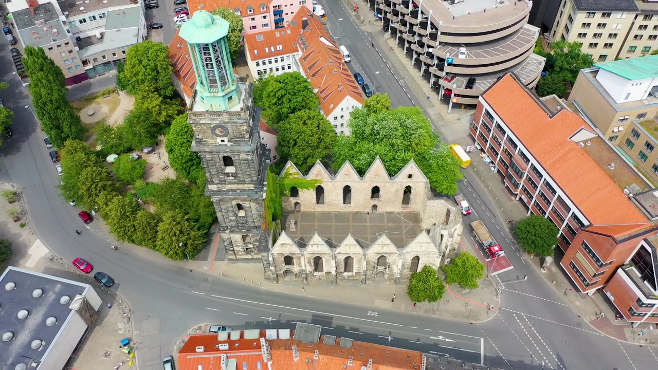Riprese aeree cinematografiche che mostrano le rovine storiche della chiesa di Aegidienkirche e la sua torre nella vivace città di Hannover, Germania