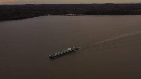 aerial shot over a turqiuse colored barge - tugboat on the hudson river on a cloudy evening in beacon, ny