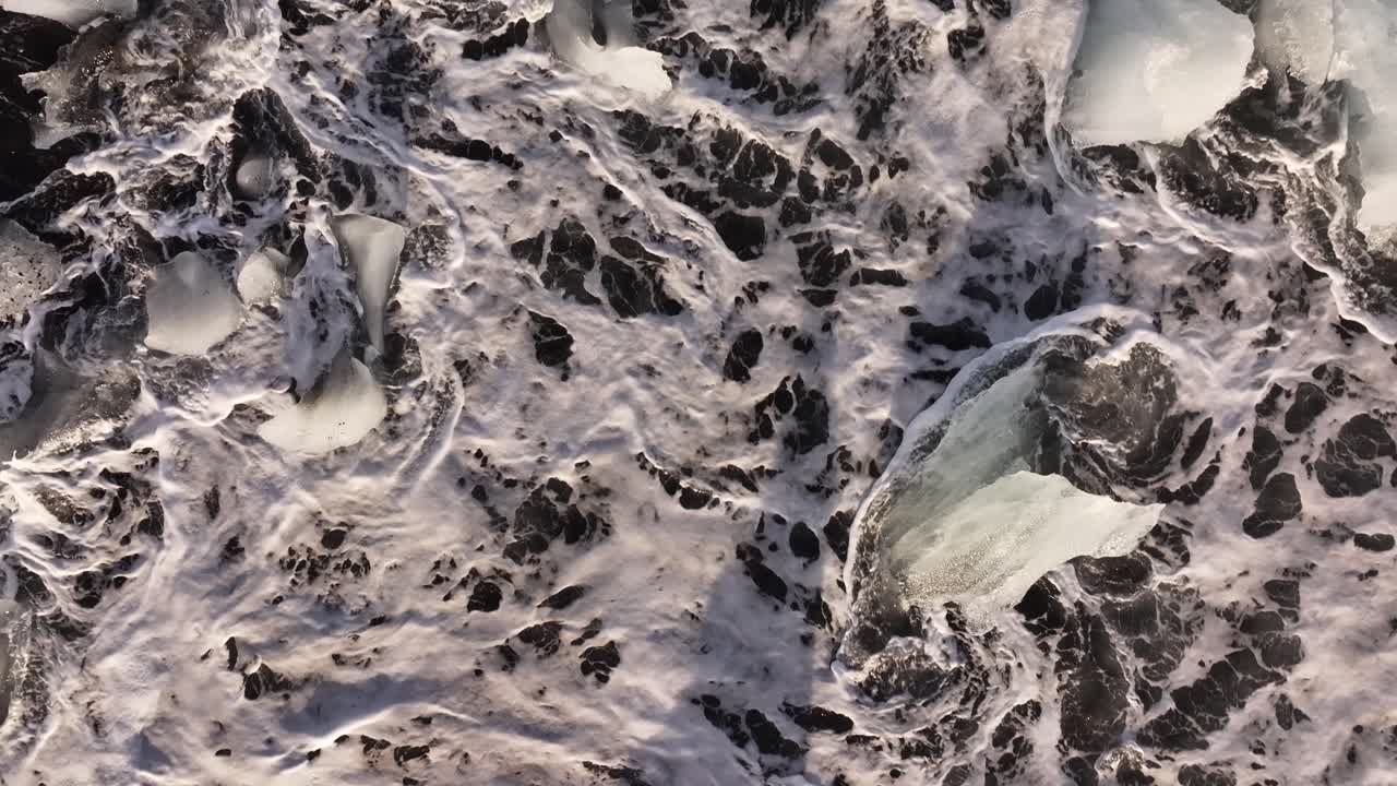 glacial ice resists the tide on dark volcanic shore in Iceland