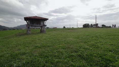slow dolly shot moving backwards close to the meadow, horreo, traditional granary from the north of spain in a cliff next to the sea in cadavedo