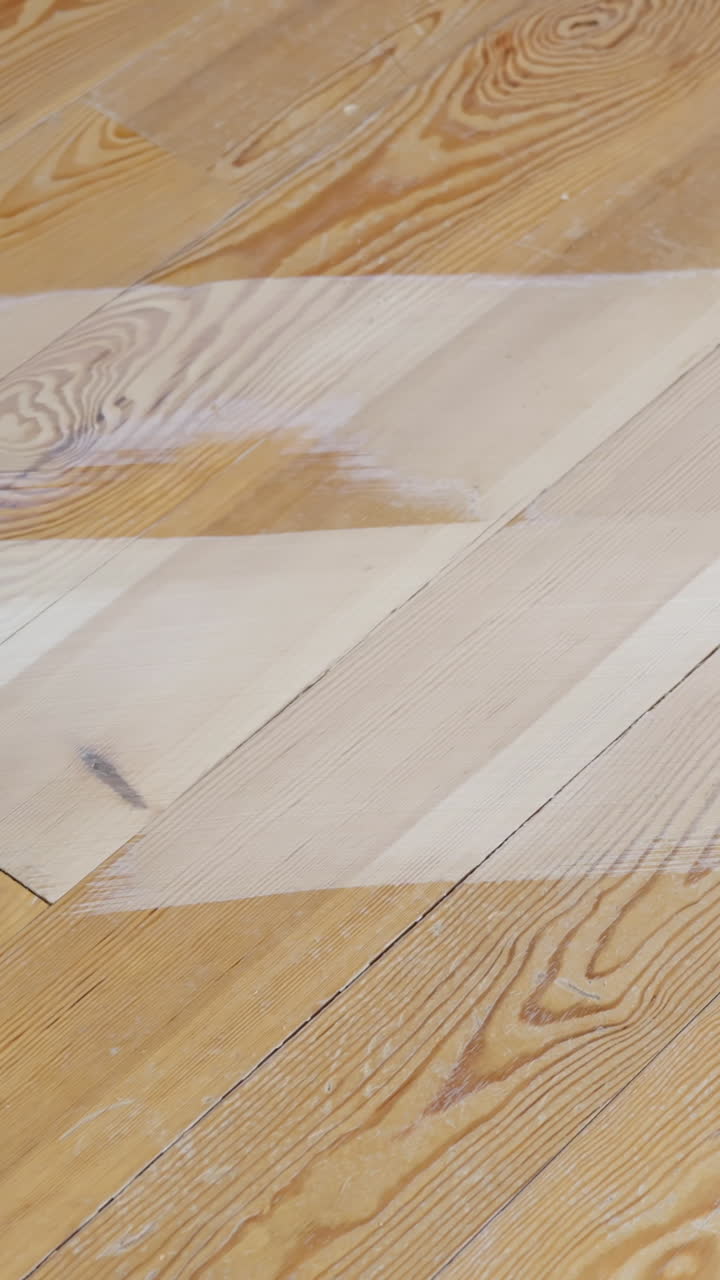 Industrial sanding machine working on pine floor surface indoors, vertical format