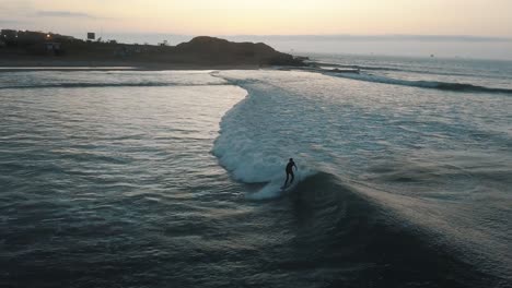 drone aerial view of a surfer in the beautiful ocean of peru during sunrise