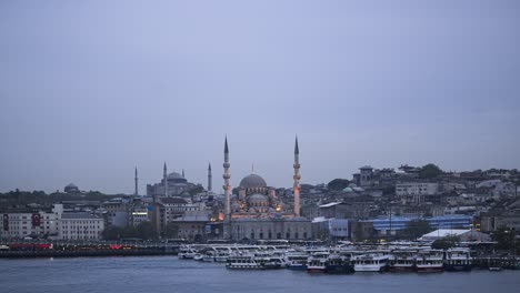 day to night timelapse in istanbul, turkey. time lapse of new mosque (yeni cami) on the banks of the golden horn and bosphorus river at night with hagia sophia (aya sofya) behind