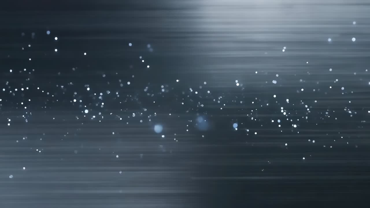 Playing particles sliding across dark gradient, creating motion blur with blue specks and bokeh