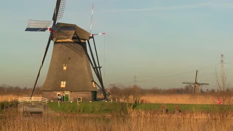 A-woman-rides-a-bicycle-past-a-windmill-in-Holland