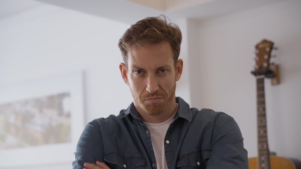 angry young man. guy looking straight at the camera with an upset expression. disappointment or hurt feelings. man portrait with his hands corssed on his chest. looking mad and unhappy with somthing
