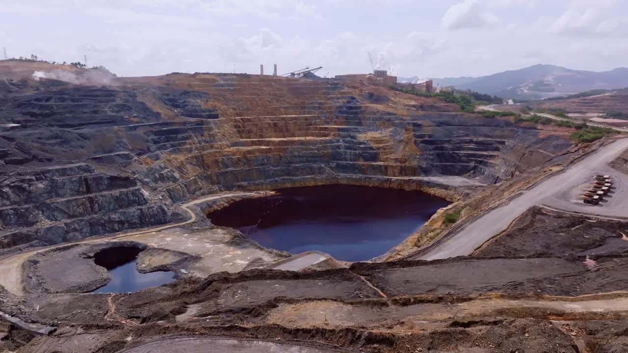 Lake in gold mine of Cotui, Dominican Republic. Aerial forward wide shot. Clouds at sky in summer. Hills with stairs and lake in valley.