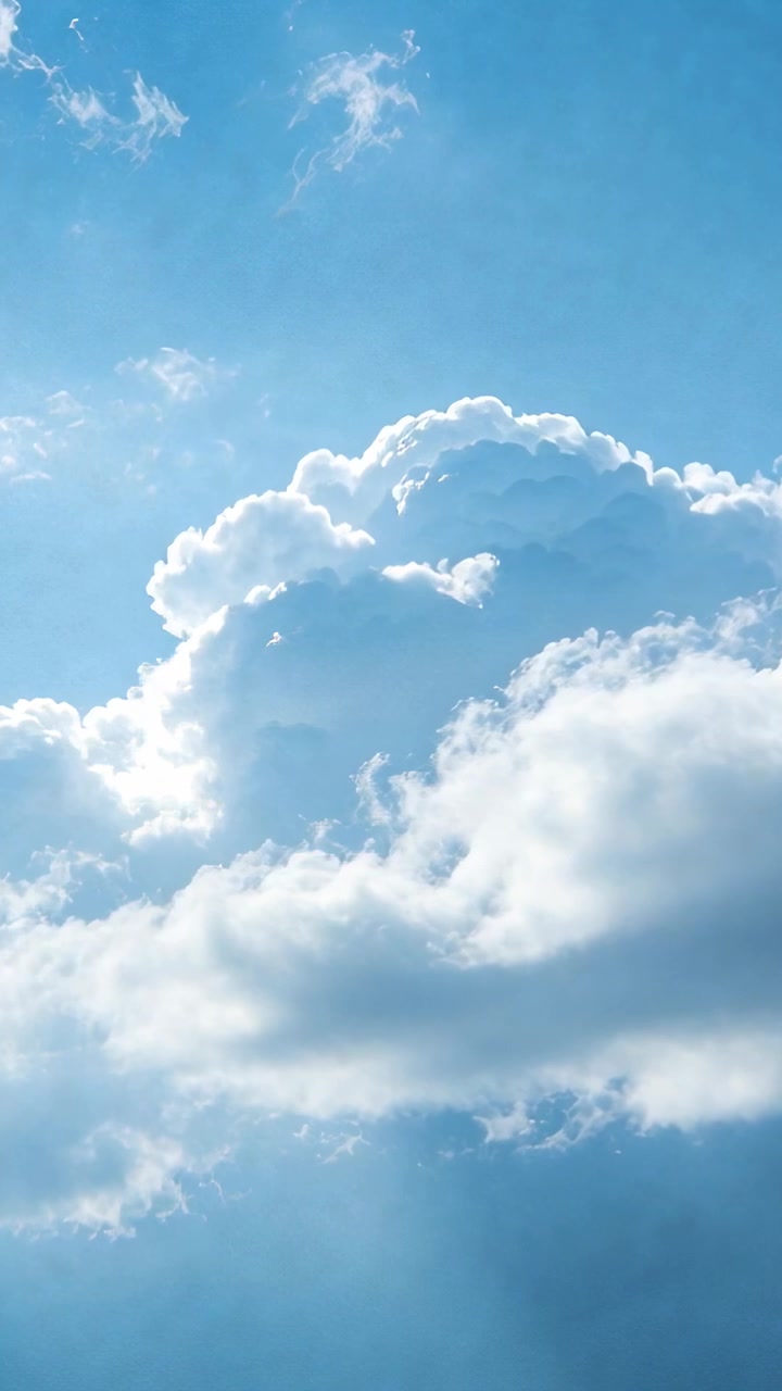 Video verticale: Nuvola cumuliforme retroilluminata che si muove, rimodellata dal vento in un cielo verticale, proiettando fasci di luce