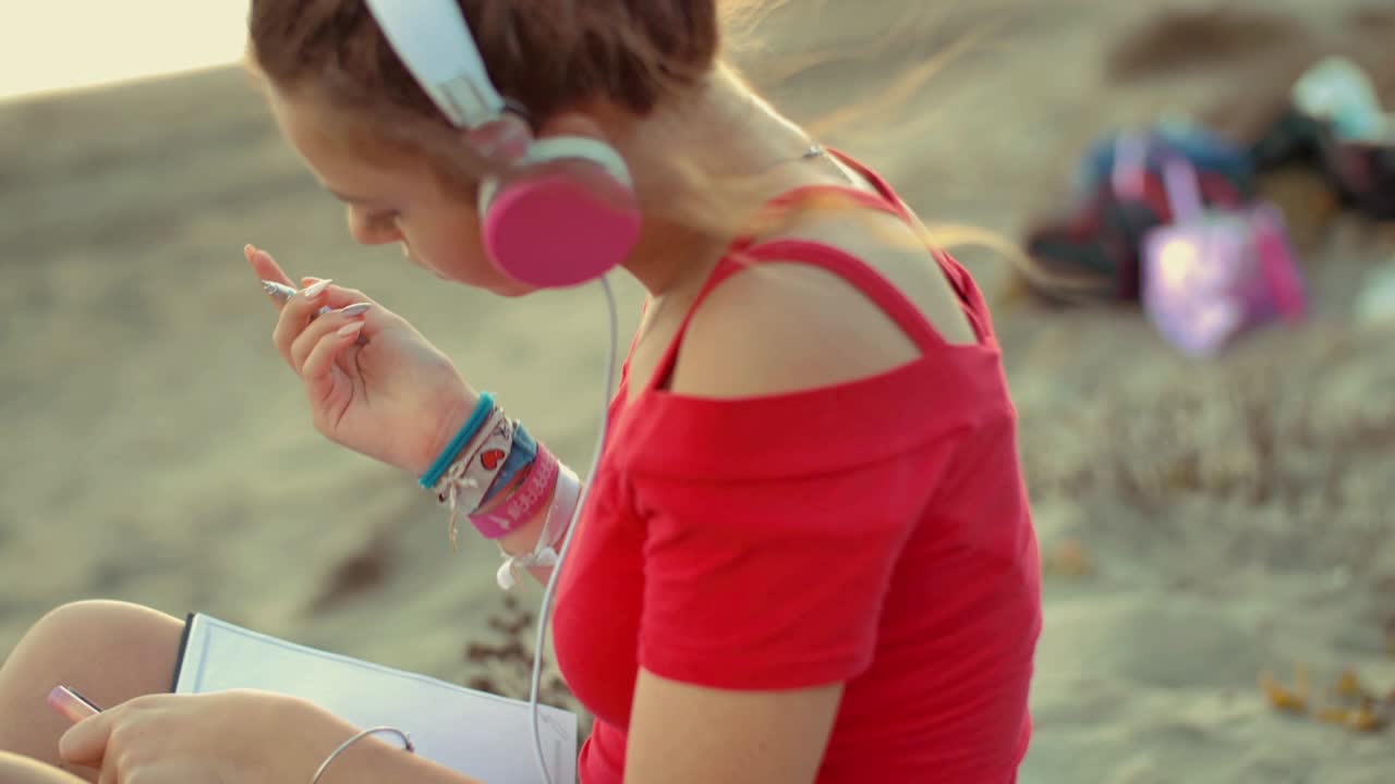chica adolescente en la playa escribiendo en su diario. rodado en cámara lenta