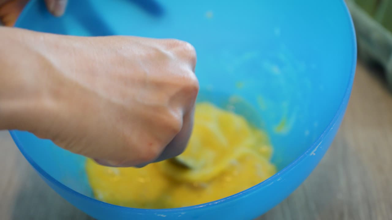 close-up shot of a woman whisking multiple eggs in a bowl with a fork
