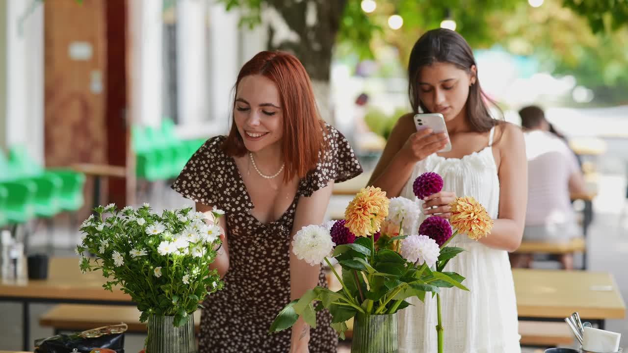 두 명의 여성이 카페에서 꽃의 사진을 찍고 있습니다.
