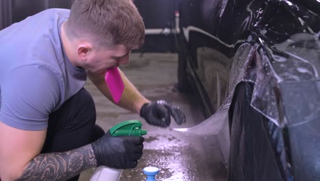 hombre que cubre el coche con cinta de poliuretano de vinilo. películas para el coche. pegatina película protectora en el coche