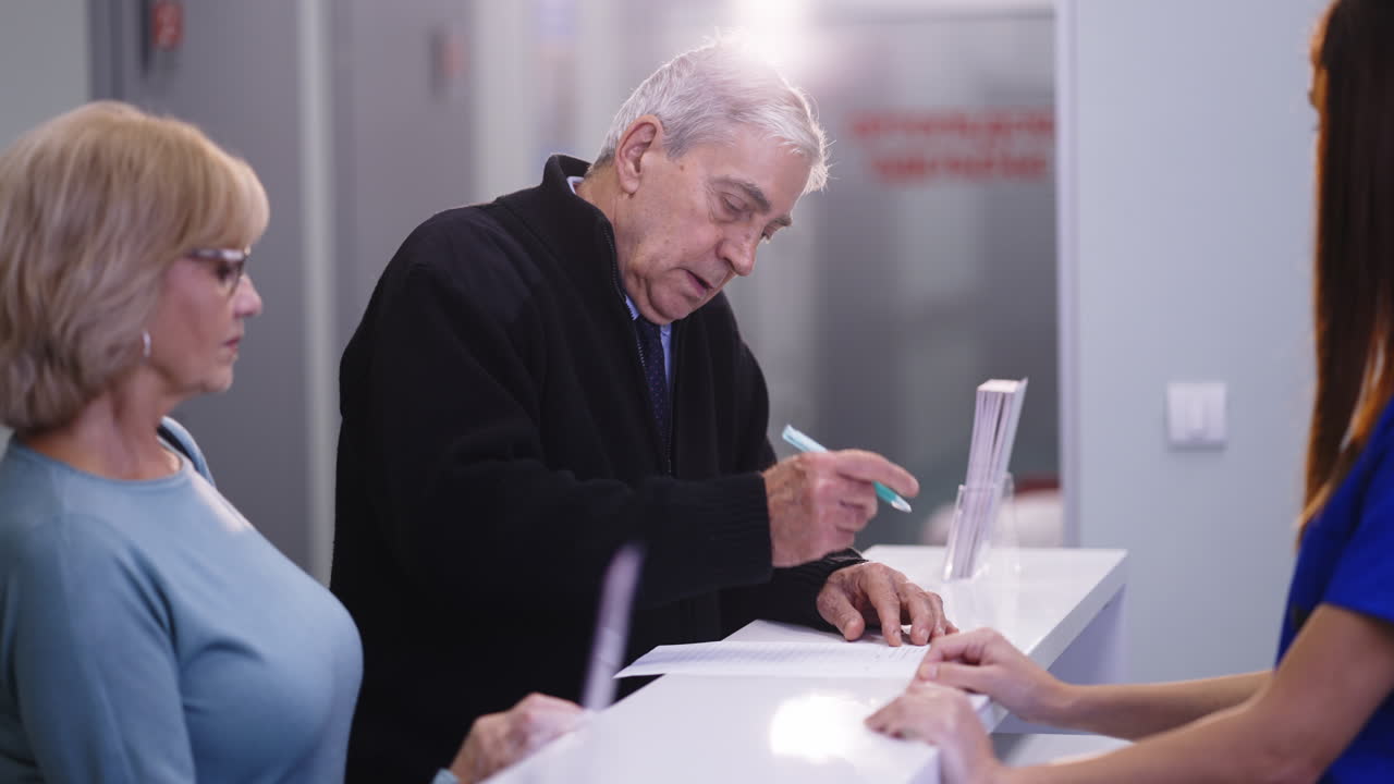 Senior couple filling out medical forms at a clinic reception