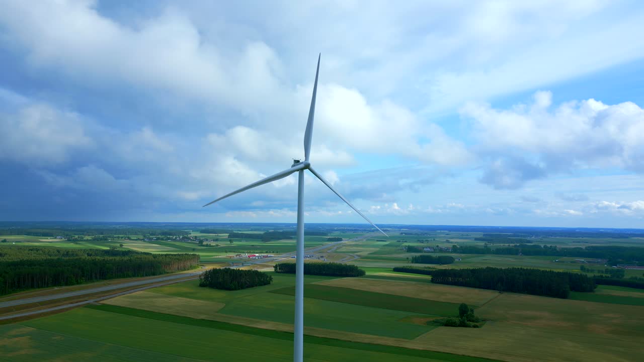 fotografía en perspectiva aérea de una turbina eólica que gira lentamente en una granja de energía de molino eólico en campos agrícolas con nubes hinchadas, polonia
