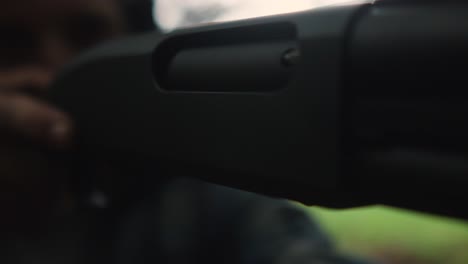 young caucasian male holding shotgun focus on the aim target victim , extremely close up of pistol weapon