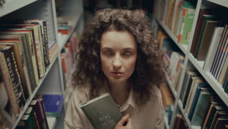 retrato de una mujer joven sosteniendo un libro en una biblioteca o librería
