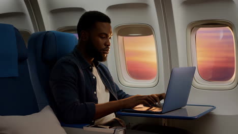 man working on laptop during airplane flight