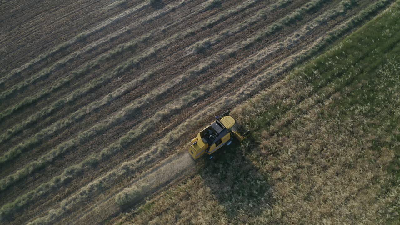una vista aérea de un granjero en un tractor con un remolque lleno de balas de paja.