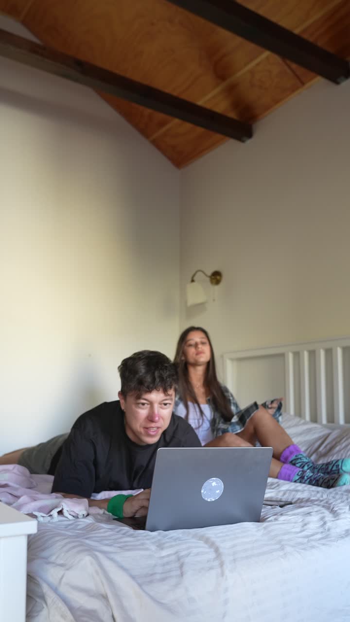 Couple Relaxing on Bed with Laptop