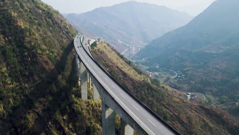 Side-View-Of-Trucks-Cars-Vehicles-Passing-Double-Lane-Highway-Bridge-In-The-Mountains-Motorway