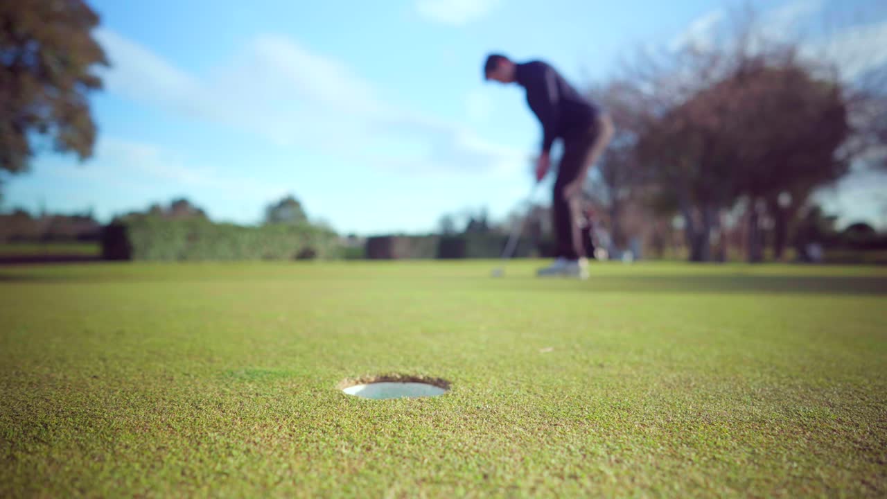 골퍼가 퍼팅 샷을 놓치고, 골프 코스의 퍼팅 그린에서 실패하고, 홀에서 클로즈업, 화창한 날