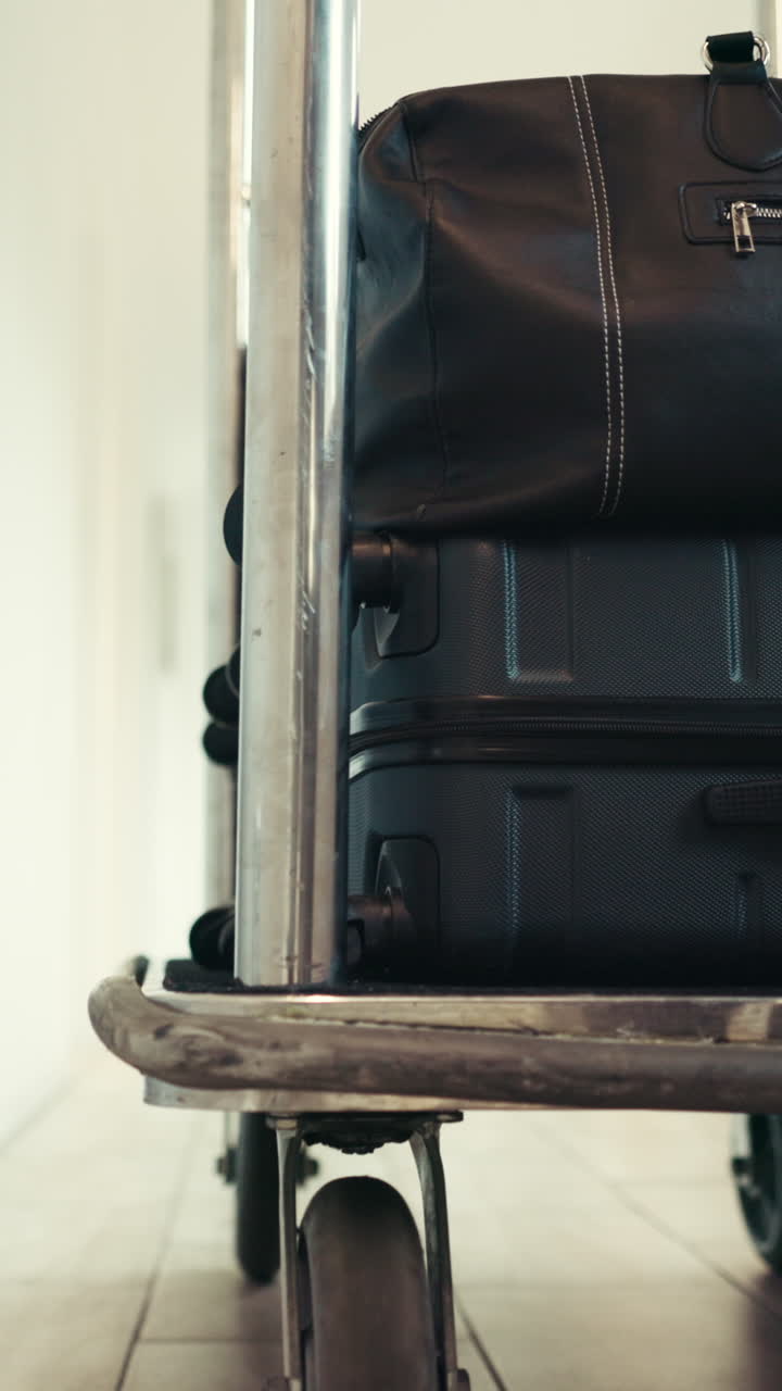 Carrello portabagagli con valigie che si muove lentamente nel corridoio di un hotel