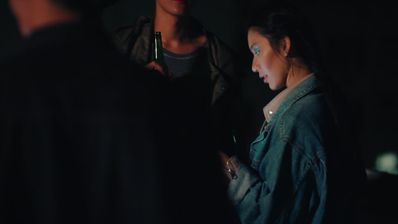 행복한 친구 그룹이 활기찬 옥상 파티 음악에 춤을 추고 스마트폰을 사용하는 젊은 아시아 여성 소셜 미디어에서 주말 축하를 공유하고 도시 야간 생활을 즐기고 있습니다.