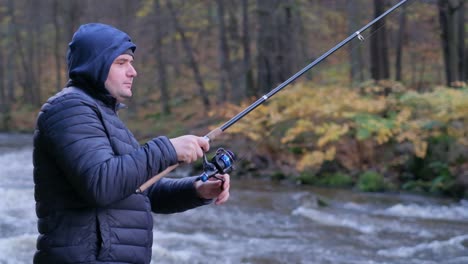 a middleaged fisherman in black clothes on a mountain river on a cloudy autumn day a middleaged fisherman in black clothes on a mountain river on a cloudy autumn day a man stands against the background of a raging mountain river to get fresh fish water hunting