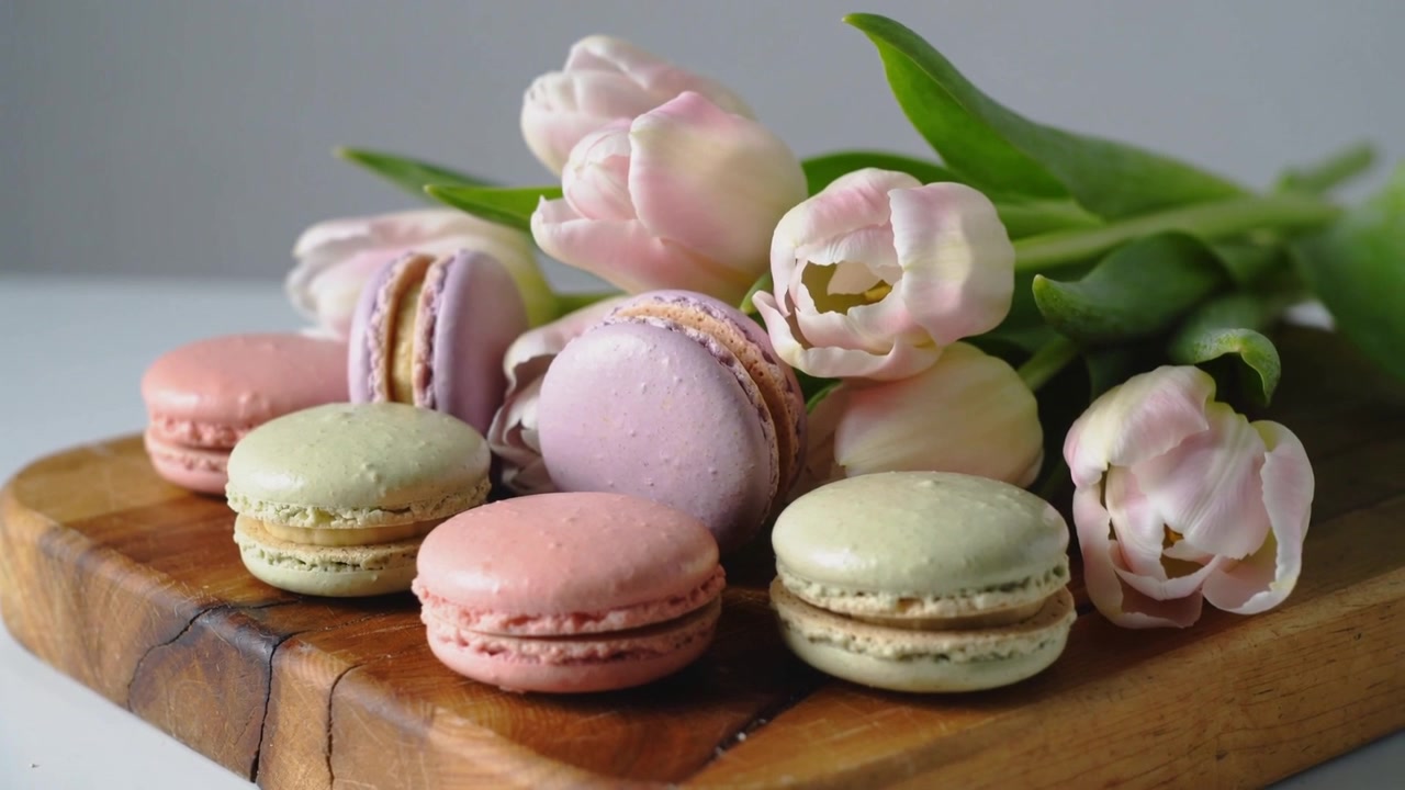 Shifting camera adjusting focus on pastel macarons on cutting board, showcasing tulip details