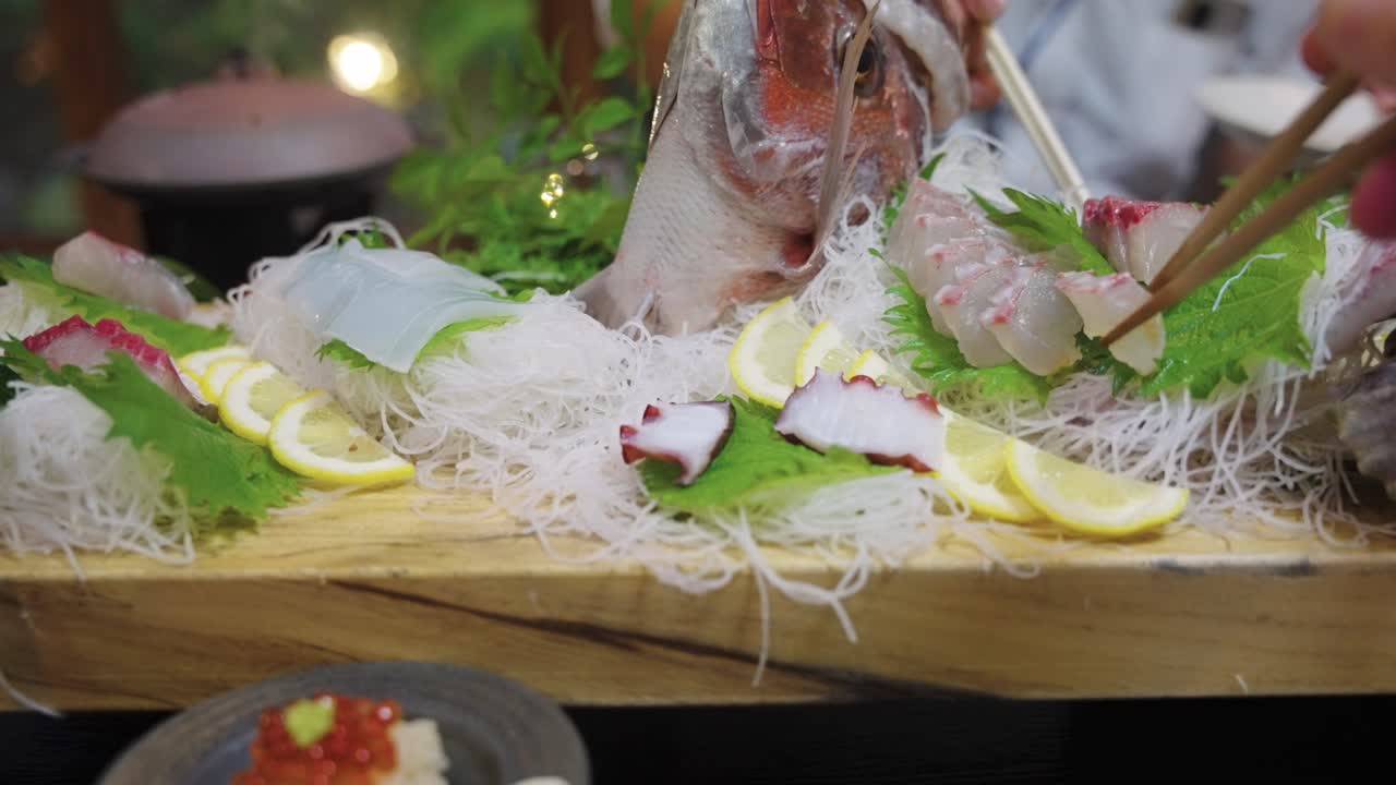 Raw Sea Bream (Japanese Tai) Sashimi being Eaten with Chopsticks at Banquet