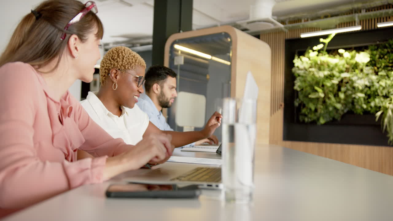 Using laptops, diverse colleagues collaborating on project in modern office