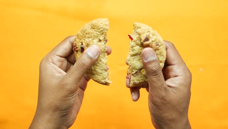 Overhead-view-of-breaking-sweet-cookies-on-orange-background-,