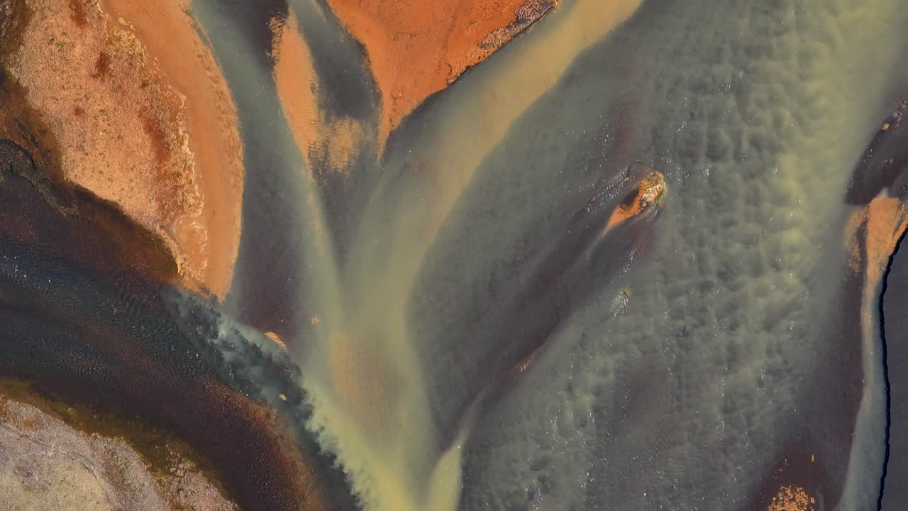 Braided River in different colors on Iceland island. Aerial top down shot. Volcanic island with erosion sediments, mud and sand. Flyover shot