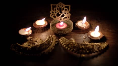 worshiping of ornate golden bridal wedding and ceremonial jewelry with blessings from lord ganesha cutout sculpture among diys candles for diwali, hindu festival of lights.