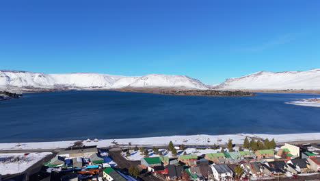 snowy coastal caviahue village beside the calm blue lago caviahue water bay in winter season, neuquén, argentina