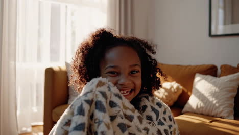 happy child playing and hiding under a cozy blanket at home